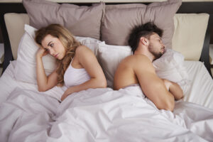 Frustrated couple laying in bed with their backs to one another
